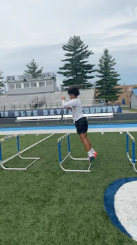 a girl jumping over hurdles on a field